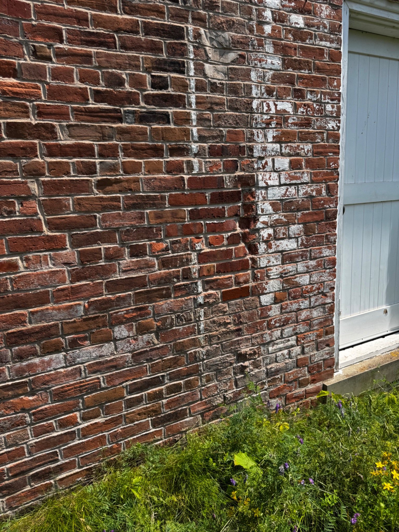Historic brick wall with multiple generations of mortar repairs and surface staining